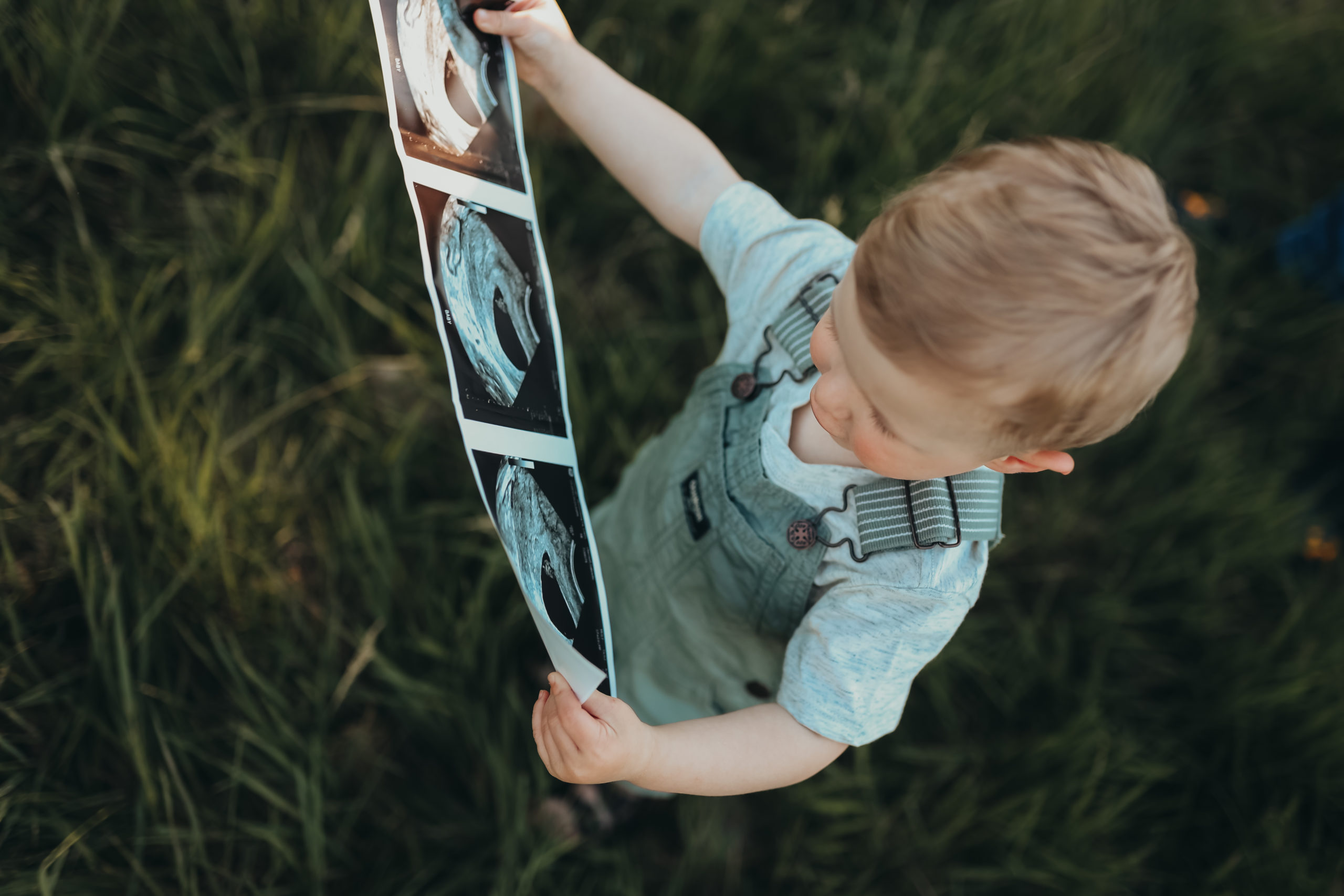 Big brother holding new babys ultrasound image